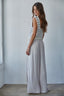 Woman wearing a striped sleeveless top and long light gray skirt against a white wall.