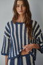 Woman wearing a blue and white striped sweater against a gray background