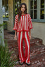 Woman wearing a red and white striped outfit standing on a brick porch.