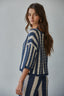 Woman wearing a blue and white striped outfit against a gray background