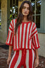 Woman wearing a red and white striped outfit standing outdoors.