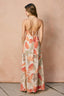 Woman wearing a blush floral maxi dress against a beige background