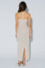 Woman wearing a beige slip dress with thin straps on a light gray background