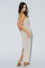 Woman wearing a beige slip dress with a slit on a white background