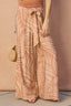 Person wearing patterned wide-leg pants with a brown background