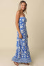 Woman wearing a blue strapless dress with white floral pattern on a beige background