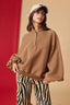 Person wearing a brown sweater and zebra print pants against a red and beige background