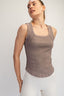 Woman wearing a brown tank top against a plain background