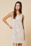 Woman wearing a sleeveless dress with floral lace details on a beige background