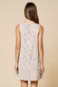 Woman wearing a sleeveless dress with floral lace details on a beige background