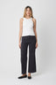 Woman wearing a white sleeveless top and black pants on a white background