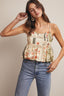 Woman wearing a floral top and blue jeans against a neutral background