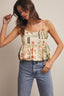 Woman wearing a floral top and blue jeans against a plain background