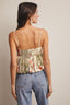 Woman wearing a patterned top and blue jeans against a neutral background