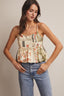 Woman wearing a floral tank top and jeans against a neutral background