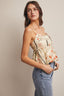 Woman wearing a floral top and jeans against a plain background