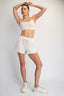 Person wearing a white sports bra and shorts set on a plain background