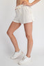 Person wearing white shorts and white sneakers on a plain background