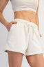 Person wearing white shorts and a white crop top on a light gray background