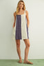 Woman wearing a sleeveless dress with purple and white stripes against a plain background