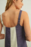 Woman wearing a two-tone dress with purple and beige straps on a plain background