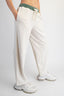 Person wearing white pants with a green waistband on a plain background