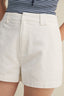 White shorts worn with a striped blue and white top on a neutral background