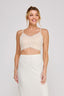 Woman wearing a beige lace top and white skirt on a plain background