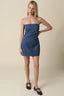 Woman wearing a denim strapless mini dress against a beige background