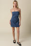 Woman wearing a denim strapless mini dress against a beige background