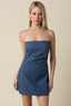 Woman wearing a denim strapless mini dress against a beige background