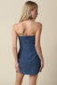 Woman wearing a denim strapless mini dress against a beige background