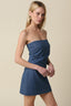 Woman wearing a denim strapless mini dress against a beige background