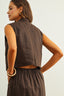 Woman wearing a brown sleeveless top and pants against a white background