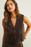 Woman wearing a brown vest against a plain background