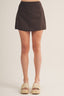 Brown suede mini skirt worn by a person on a plain background