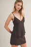 Woman wearing a brown cami tank top with a beige background