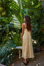Woman in a yellow dress standing among lush green plants
