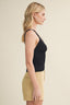 Woman wearing a black tank top and beige shorts on a beige background
