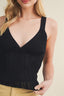 Black ribbed tank top worn by a person on a beige background