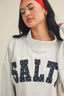 Person wearing a gray sweatshirt with 'SALT' printed on it, against a neutral background