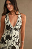 Woman wearing a black floral dress against a beige background