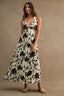Woman wearing a black floral dress against a beige background