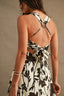 Woman wearing a black and white floral dress with an open back against a beige background
