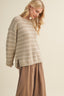 Woman wearing a striped sweater and brown pants on a beige background