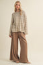Woman wearing a striped sweater and wide-leg pants on a beige background