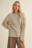 Woman wearing a striped sweater and brown pants against a beige background