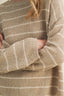 Close-up of a person wearing a beige and white striped sweater.