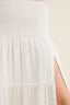 Close-up of a white strapless top with smocked detail on a beige background