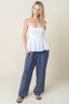 Woman wearing a white top and blue pants against a beige background